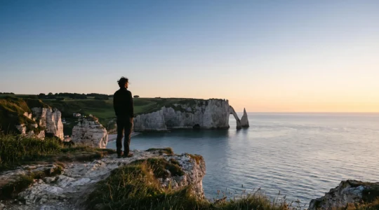 Silhouette contemplative face à des falaises françaises au lever du soleil, symbolisant la sérénité face à la finitude